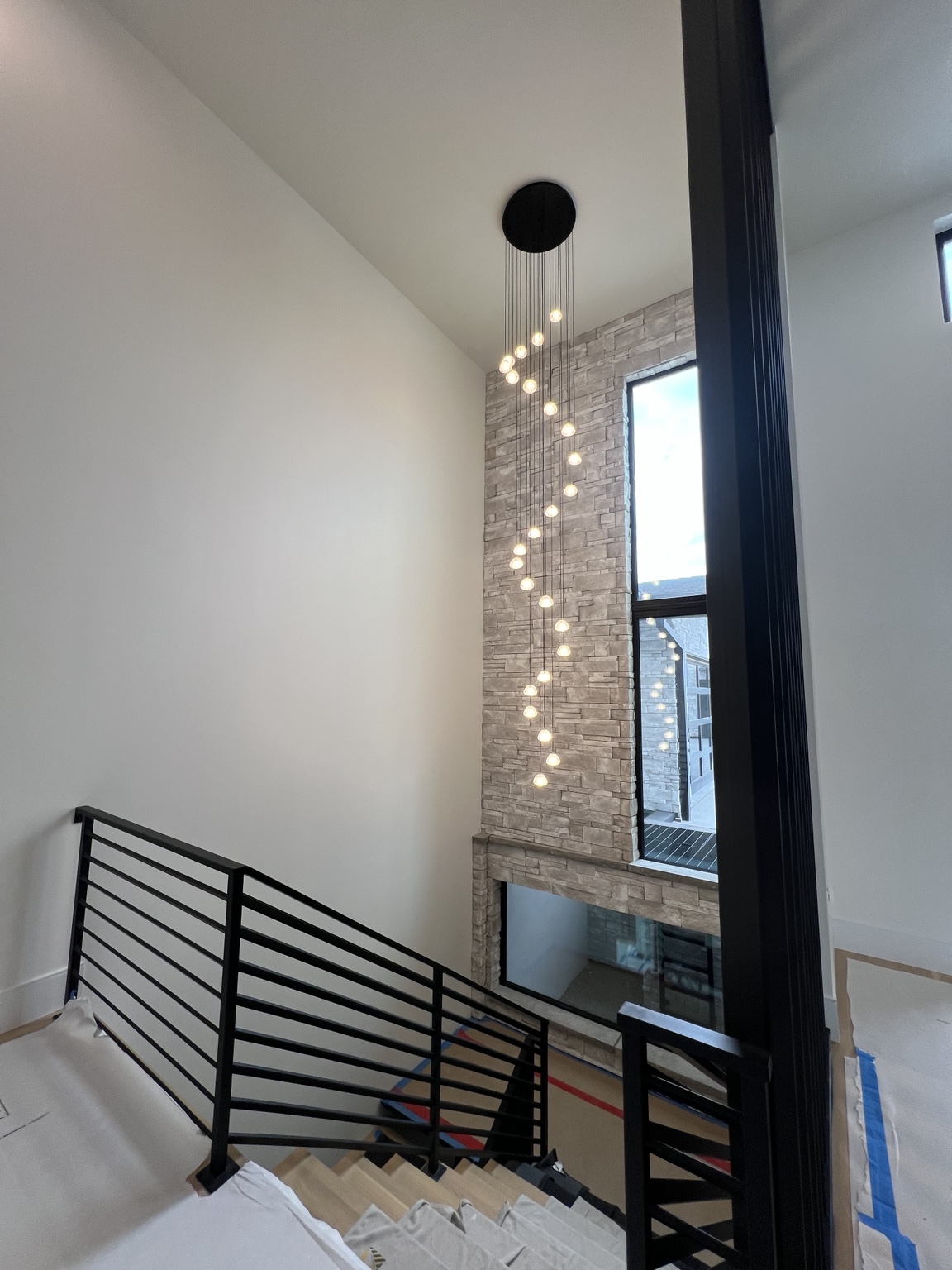 Multi-light chandelier installed over a high staircase